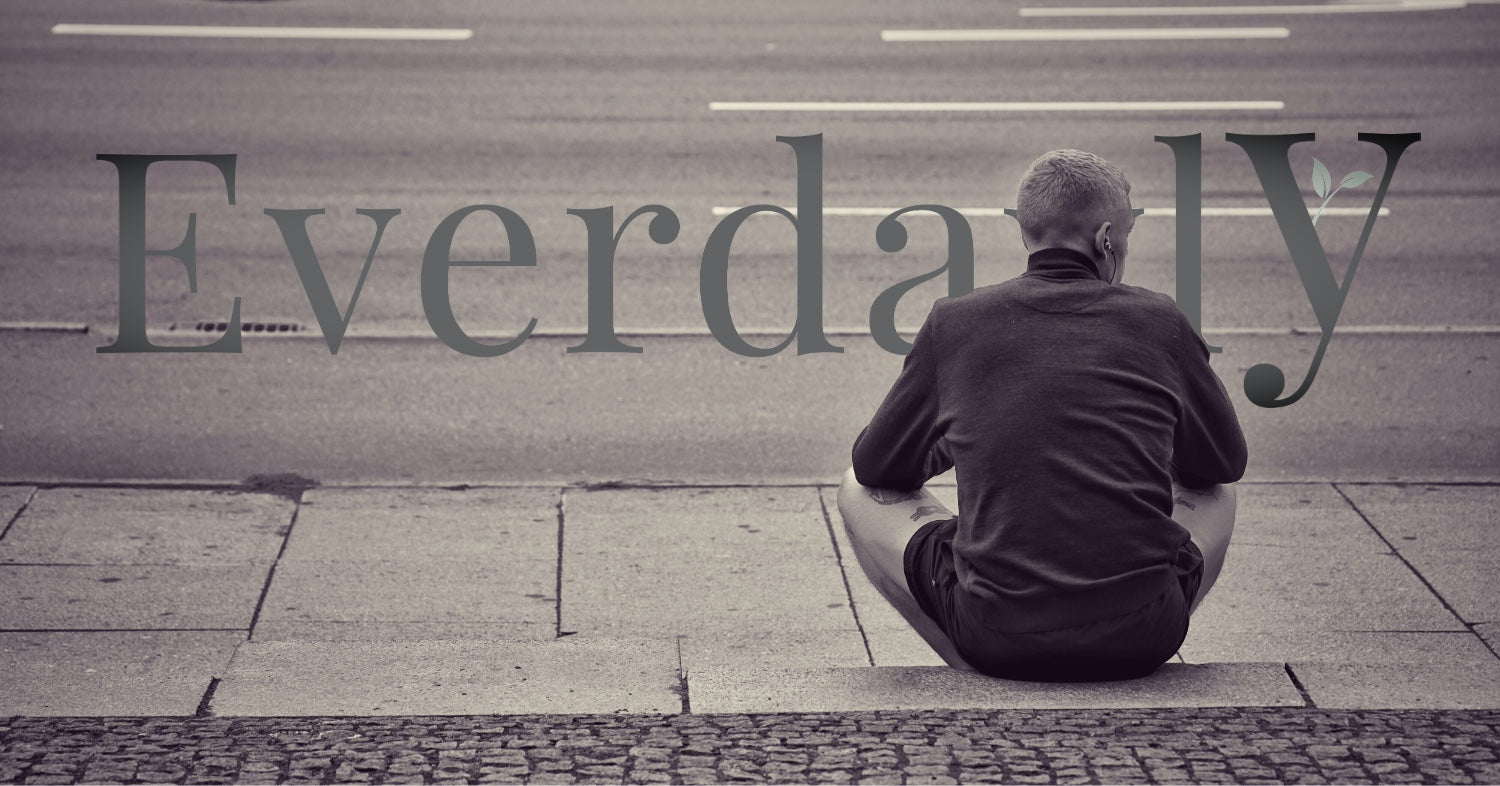 A person sitting quietly near a window with soft natural light, in a calm reflective moment for Everdayly.